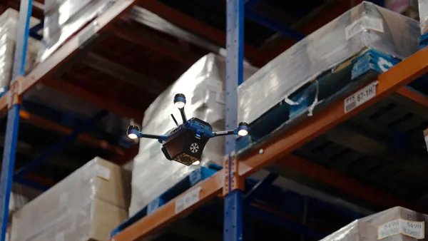 A drone hovers nearby boxes on shelves