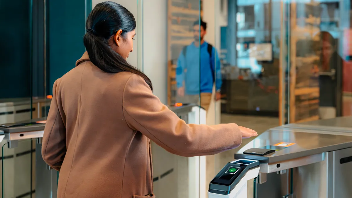 A woman uses her palm to show credentials for an access control point.