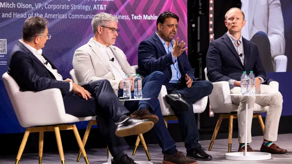 Four executives discuss the telecom industry on stage at a conference.