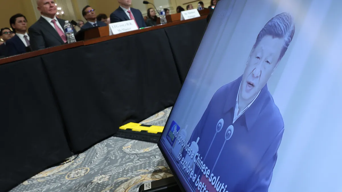 A video of Chinese President Xi Jinping is seen as a group of men in suits watch