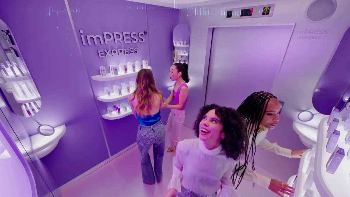 Kiss Products' "imPRESS Yourself" campaign imagery that shows several people gathered in an elevator-like beauty-pod concept looking at various Kiss products.