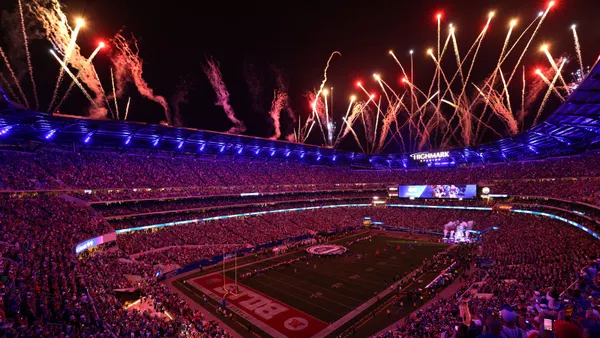 Fireworks explode over a stadium bowl at night time.
