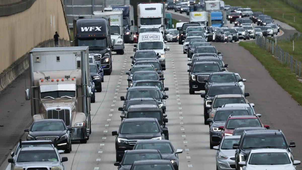 Cars and trucks lined up bumper to bumper on a three-lane highway.