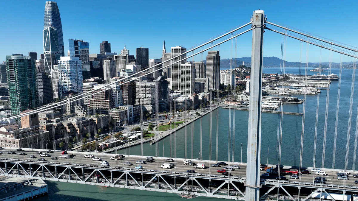 In an aerial view, cars drive by the San Francisco skyline as they cross the San Francisco-Oakland Bay Bridge on October 27, 2022 in San Francisco, California.