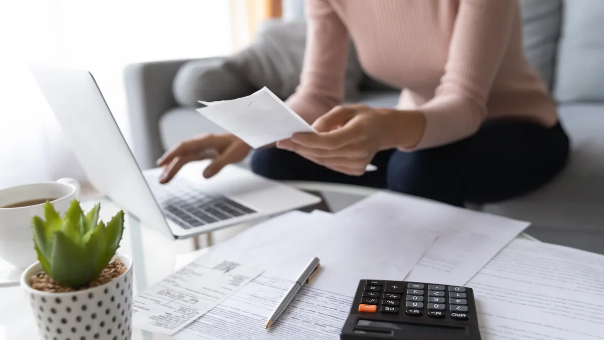 A woman on a home laptop works on a budget.