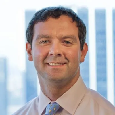 A person wearing a shirt and tie smiles for a photo