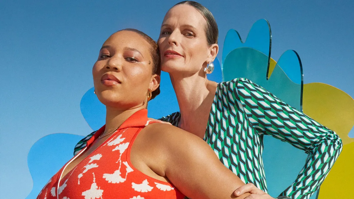 Two people stare at the screen, arms akimbo, wearing printed wrap dresses with slicked back hair.