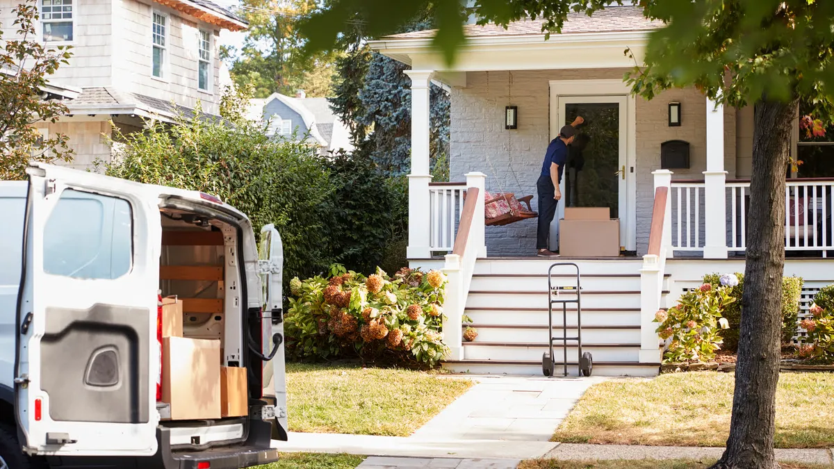 Courier Using Trolley To Deliver Package To House