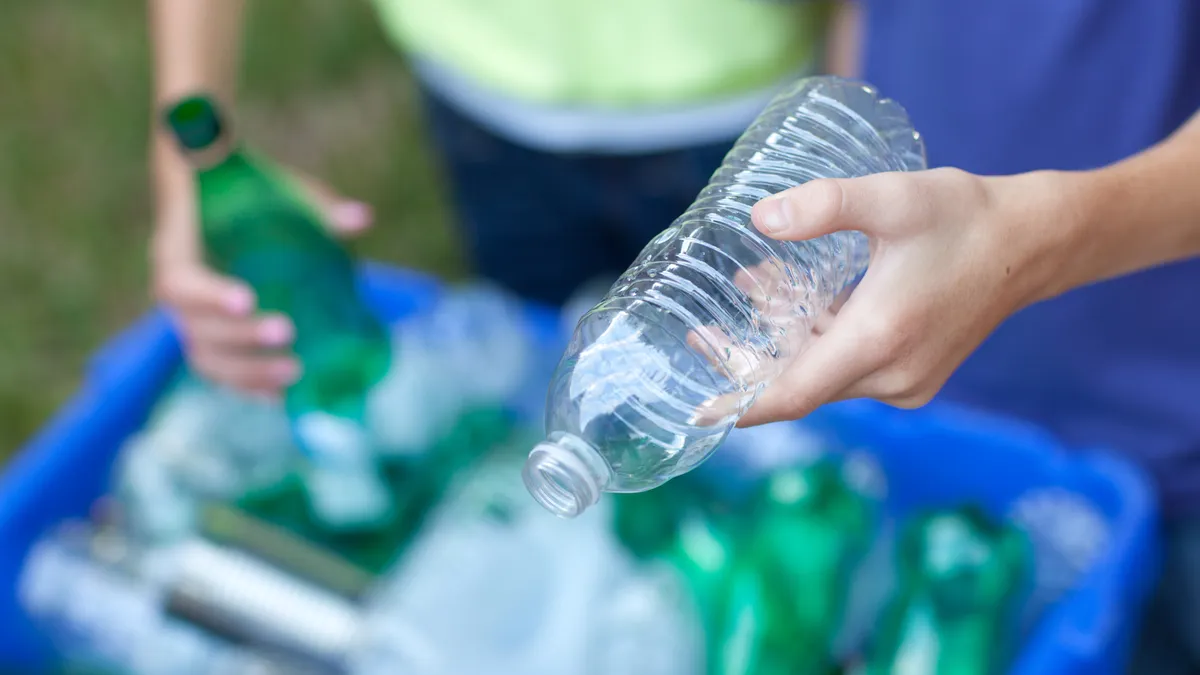 People placing bottles in recycling bin