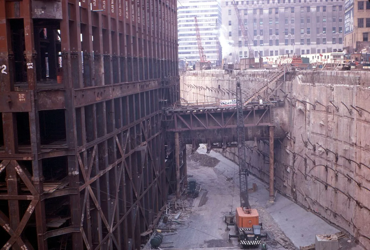 A view of a massive excavation on a construction site in a city.