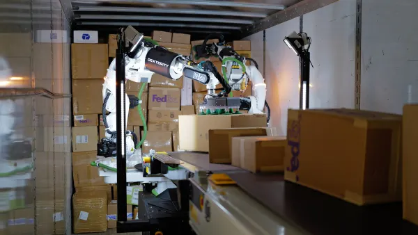 A robotic system uses an arm to move a package inside a trailer.