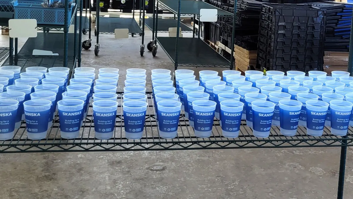 Plastic cups are lined up on a shelf in an industrial warehouse.