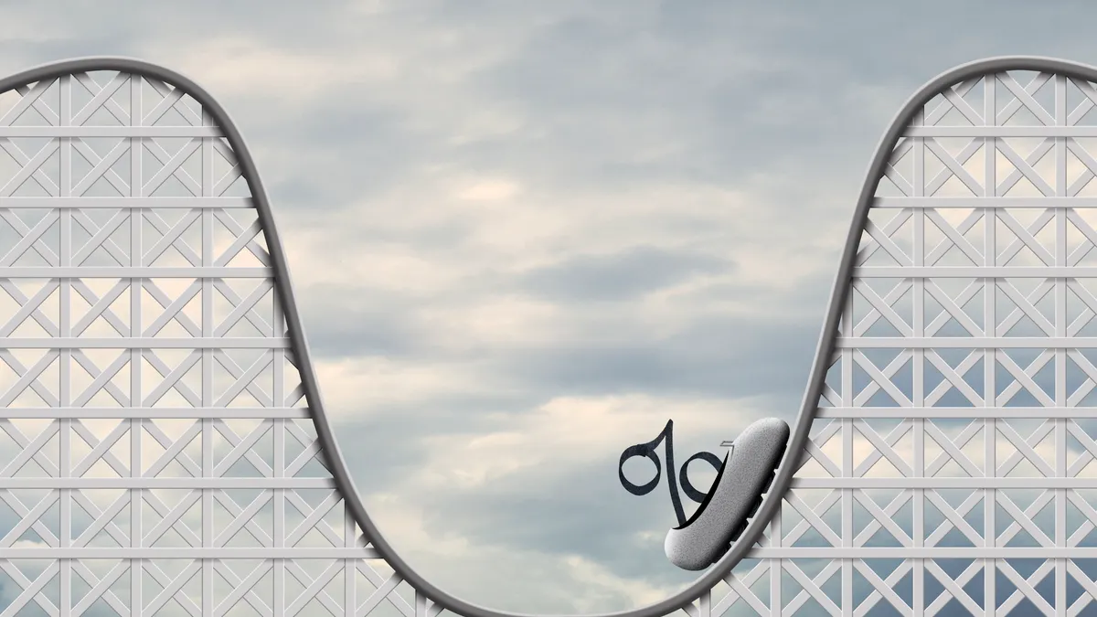 An interest rate symbol sits in a car on a rollercoaster as it begins to make its way back up.