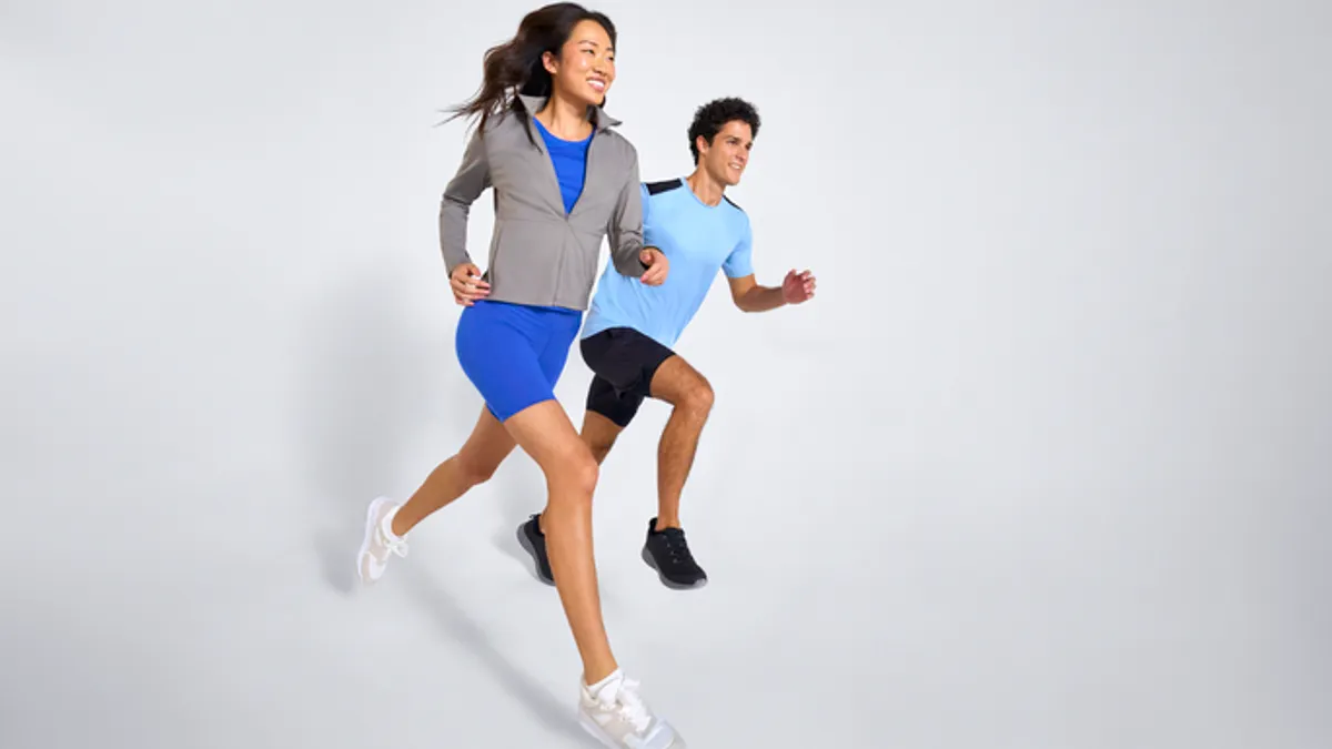 Two people in activewear running on a grey background.