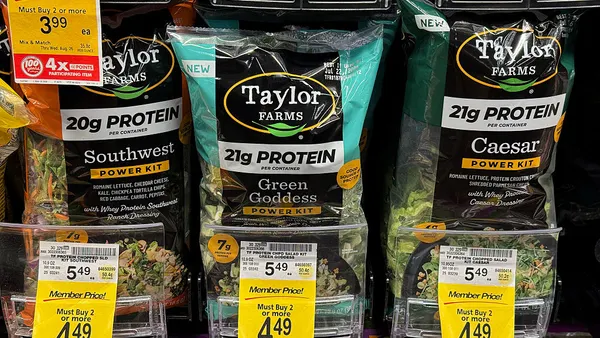 Packages of Taylor Farms salad greens on a store shelf
