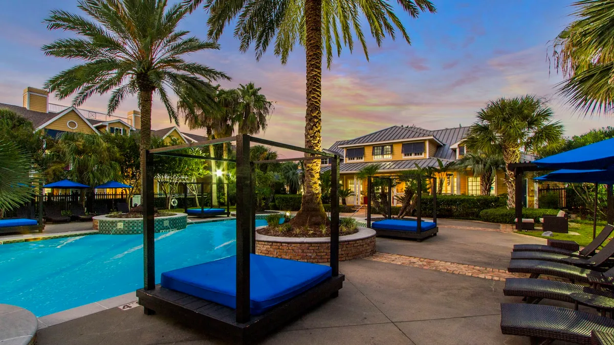 Apartment building with palm trees and a pool in the foreground