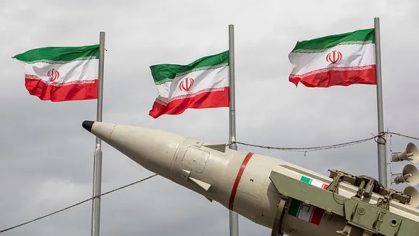 a set of missiles sit on their launches with Iranian flags in the background