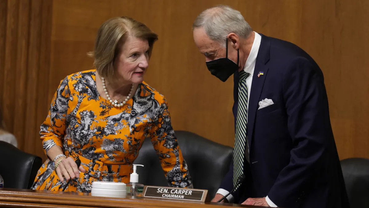 Two senators speak behind a dais