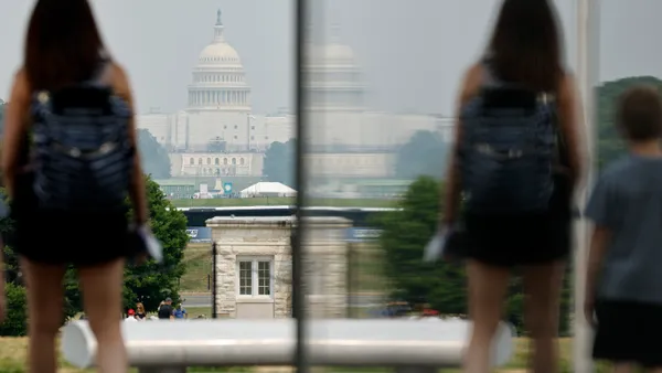 A tourist stands on the National Mall with the U.S. Capitol in the distance.