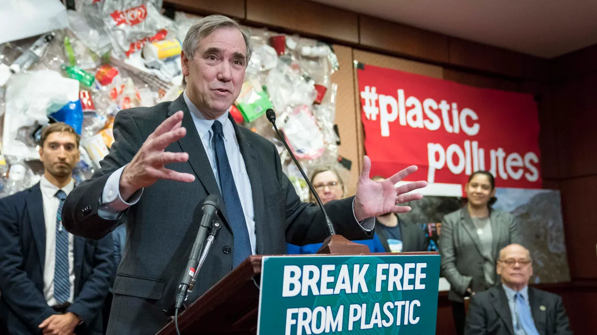 Sen. Jeff Merkley stands in front of a plastic display to introduce legislation