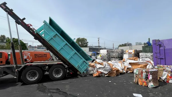 A truck dumps bales of plastic at a construction site.