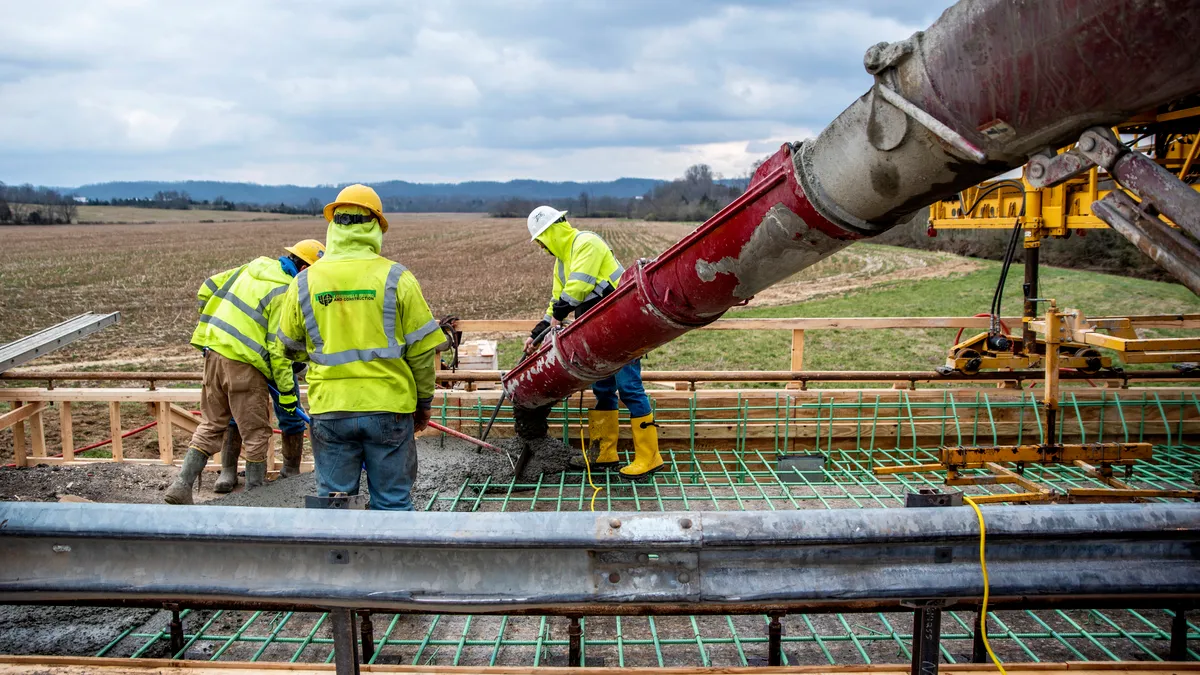 Construction workers in reflective vests work on building a bridge.