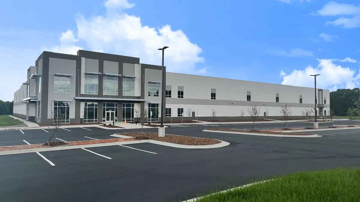 A gray building with an empty parking lot in front of it.