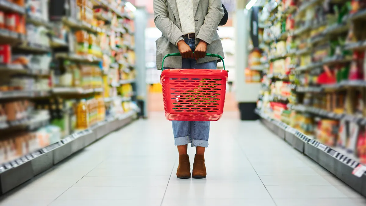 A woman stands in a supermarket aisle.