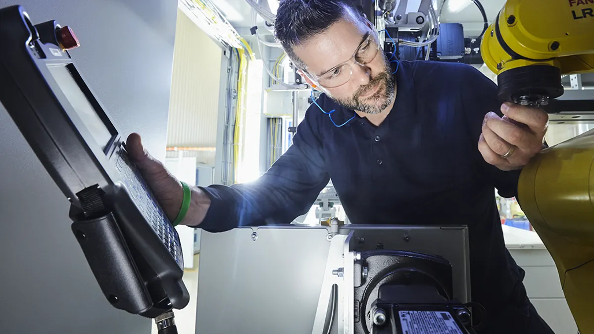 Person wearing glasses and working with various pieces of technology.