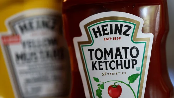 Bottles of Kraft Heinz ketchup and mustard are displayed side by side. One bottle reads "Heinz Estd. 1869 Tomato Ketchup 57 Varieties." The other bottle's label is blurred.