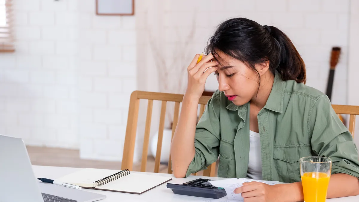 An Asian woman sits at a table doing bills.