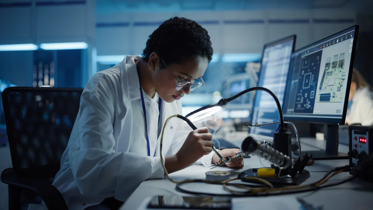 An engineer works on a printed circuit board.