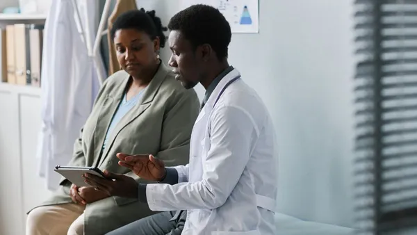 Side view portrait of doctor and patient talking in a clinic setting.