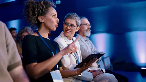 People at a conference look at a tablet.