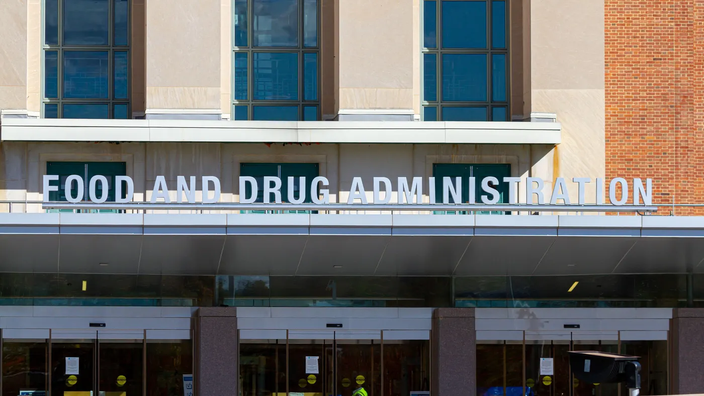 A modern architectural design building featuring a red-brick façade with large glass windows displays a prominent sign of the Food and Drug Administration. 