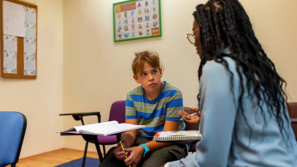 A student sits at a desk while listening to a school counselor.