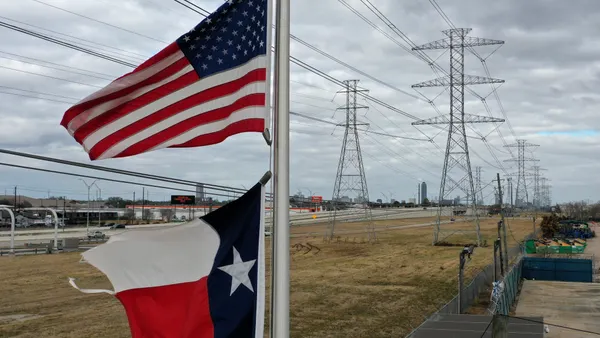 he U.S. and Texas flags fly in front of high voltage transmission towers