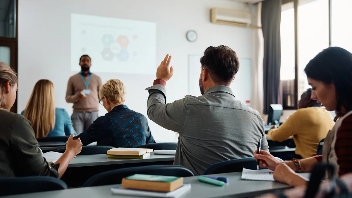 A student raises their hand during a college lecture.