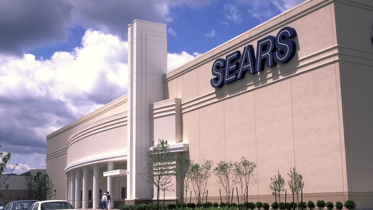 The exterior of a Sears store with cars in the parking lot