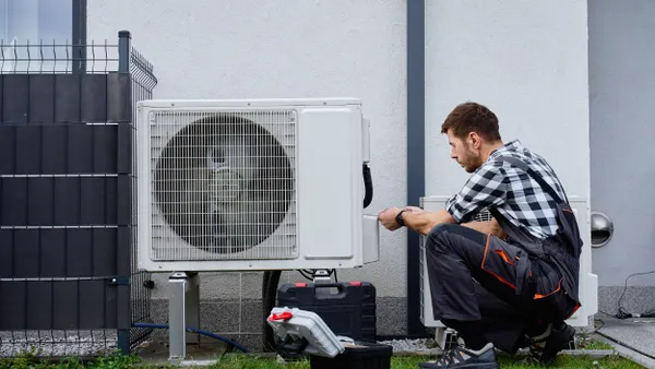 Person performing maintenance on outdoor heat pump