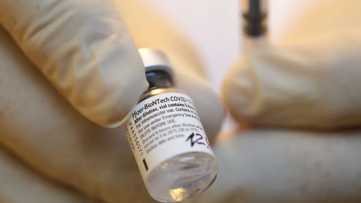 pfizer-biontech covid vaccine bottle in gloved hand