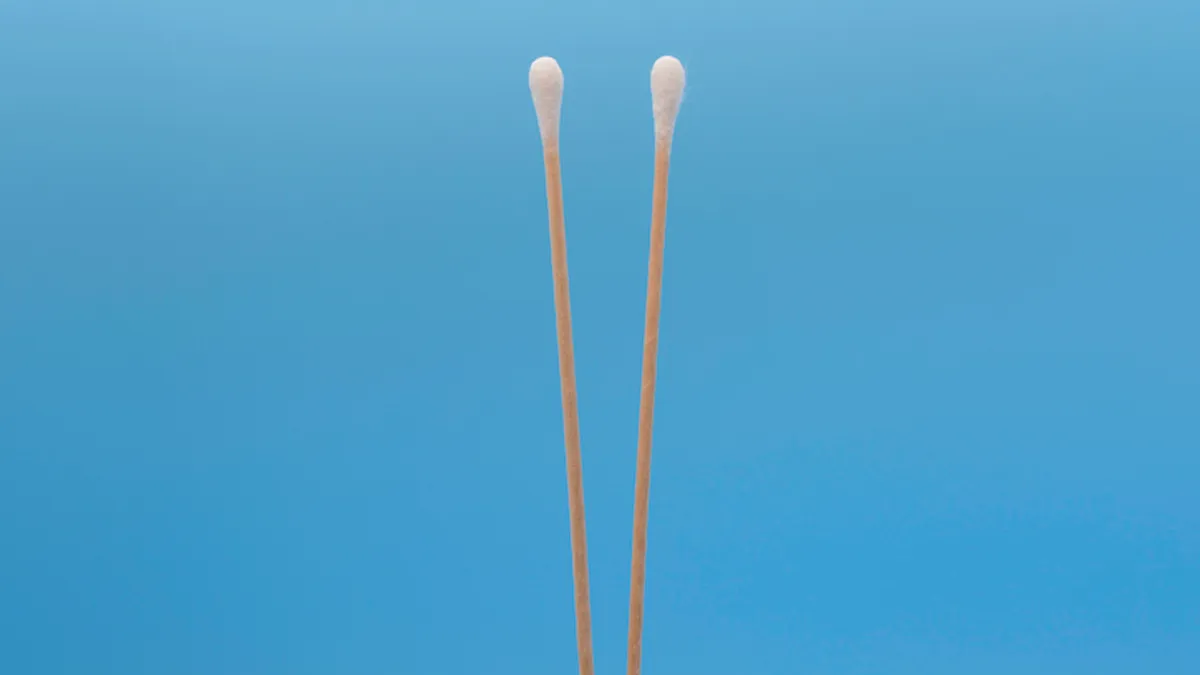 Two nasopharyngeal swabs in front of a blue background