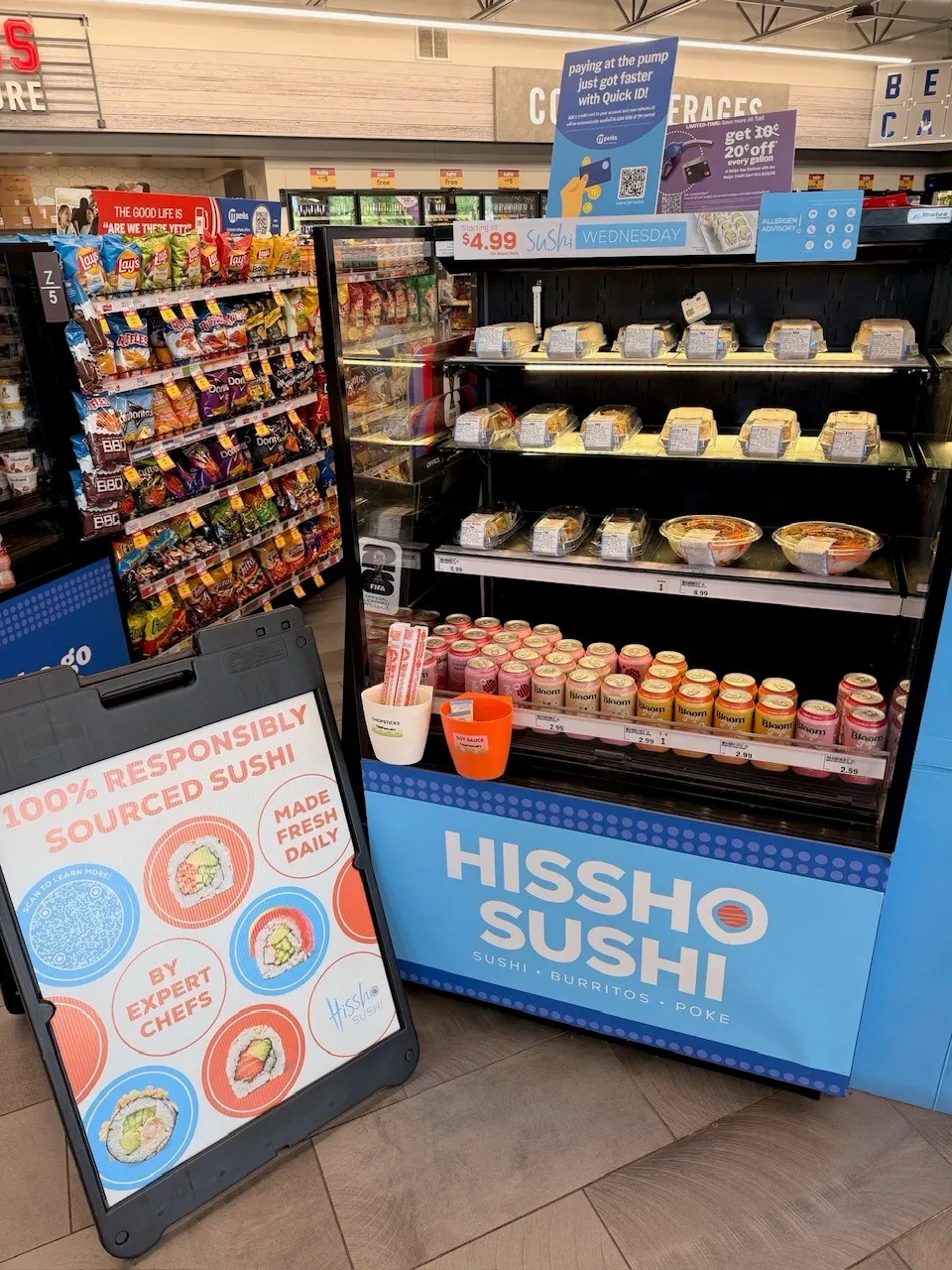 A sushi display inside a convenience store. A sign on the display says Hissho Sushi while a sign nearby says 100% responsibly sources sushi.