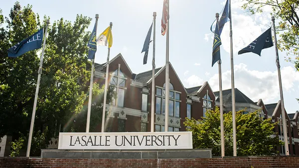 Brick building lined in front with flag poles, including the flag for La Salle University.