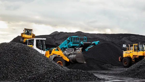 Caterpillar tractors collect black coal pile.