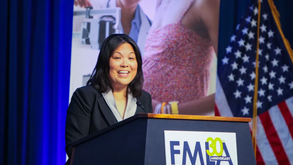 Julie Su is seen speaking at a podium.