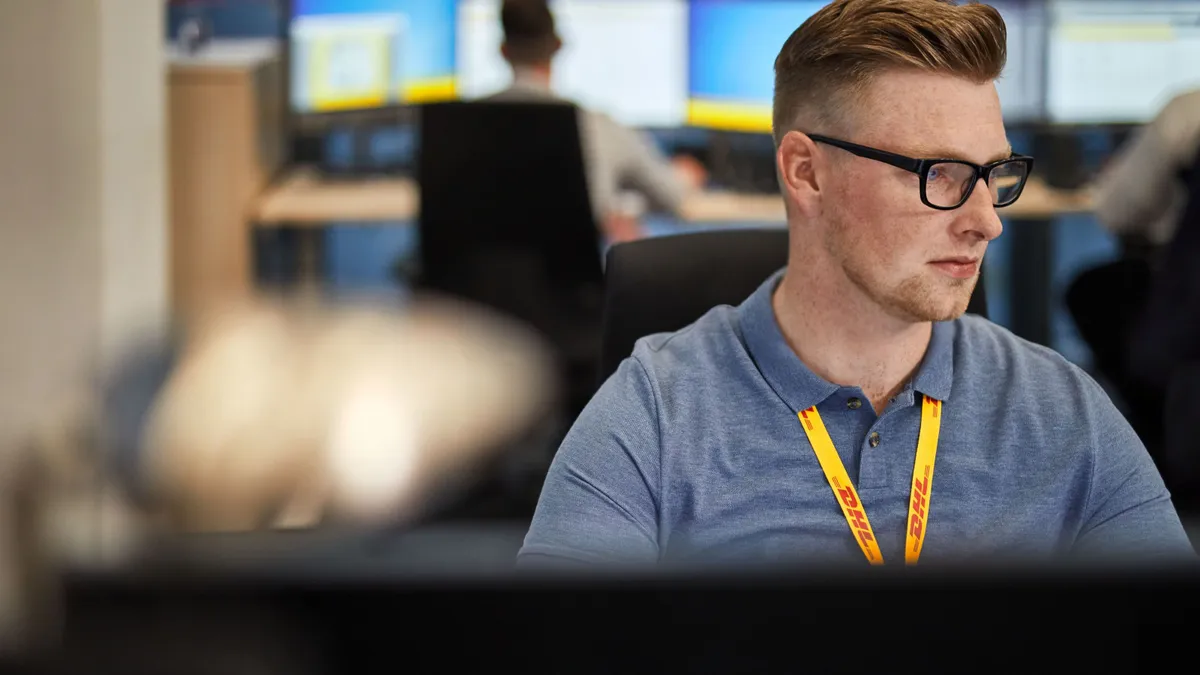 A DHL employee sits in front of a computer.