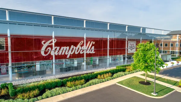 A long rectangular building with five rows of glass windows and the red and white Campbell's logo.