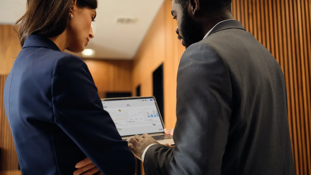 Two people working and looking at a graph on a laptop.