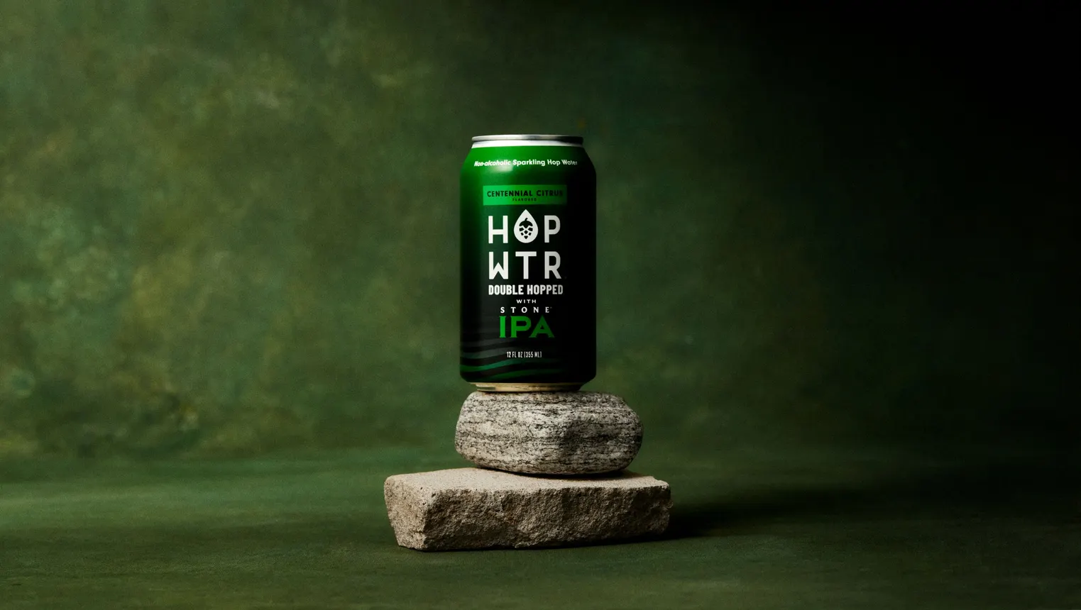 A can of the collaboration between Stone Brewing and Hopwtr sits on a rock.